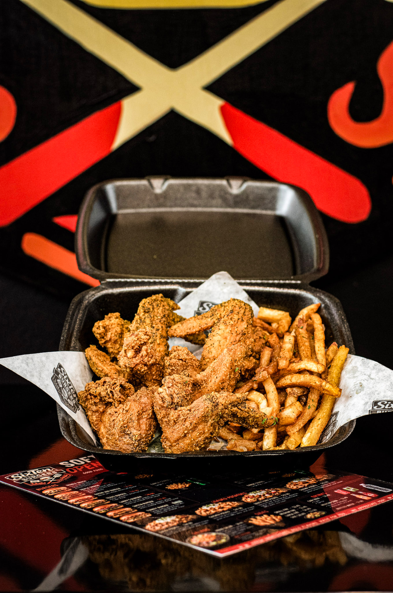 Fried whole wings with seasoned fries in a SixTen takeout box
